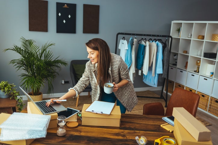 Woman working at a desk with a laptop and boxes.