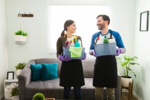 A couple holding baskets of cleaning supplies looking at each other