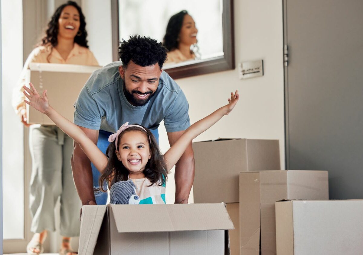 A father pushing his daughter in a moving box with her arms out
