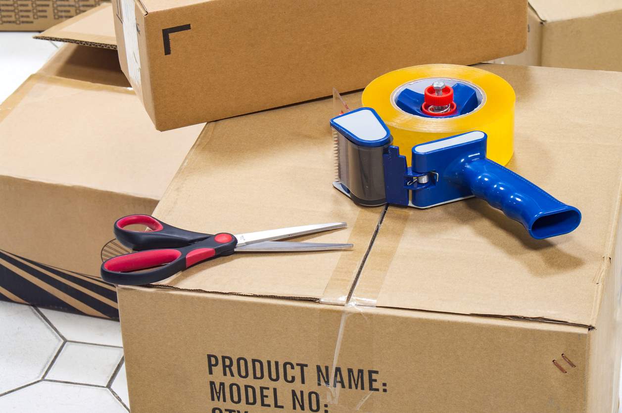 A pair of scissors and tape on top of a packed box