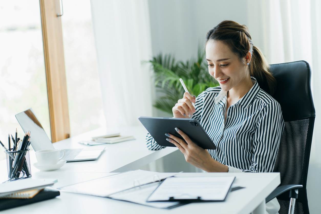 A woman writes on her iPad in her office.