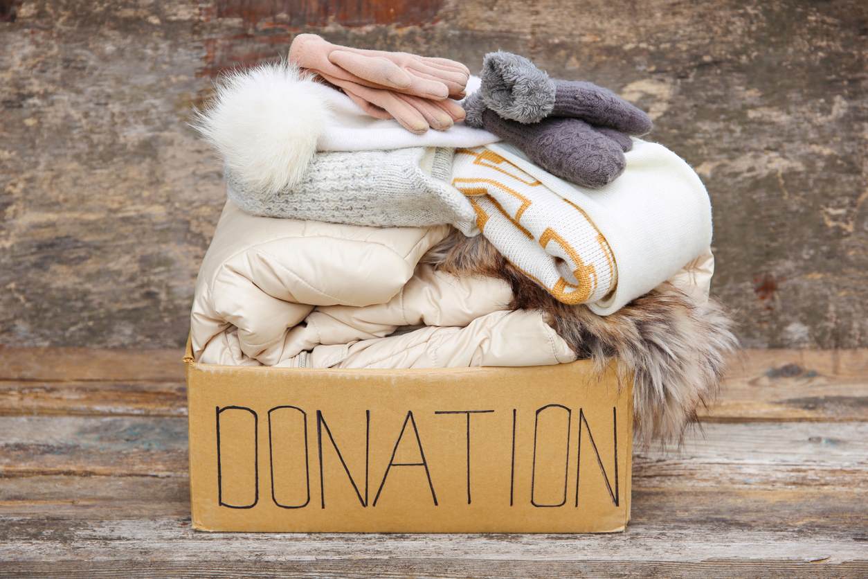 Winter clothing piled in a cardboard box labeled “donation.” 
