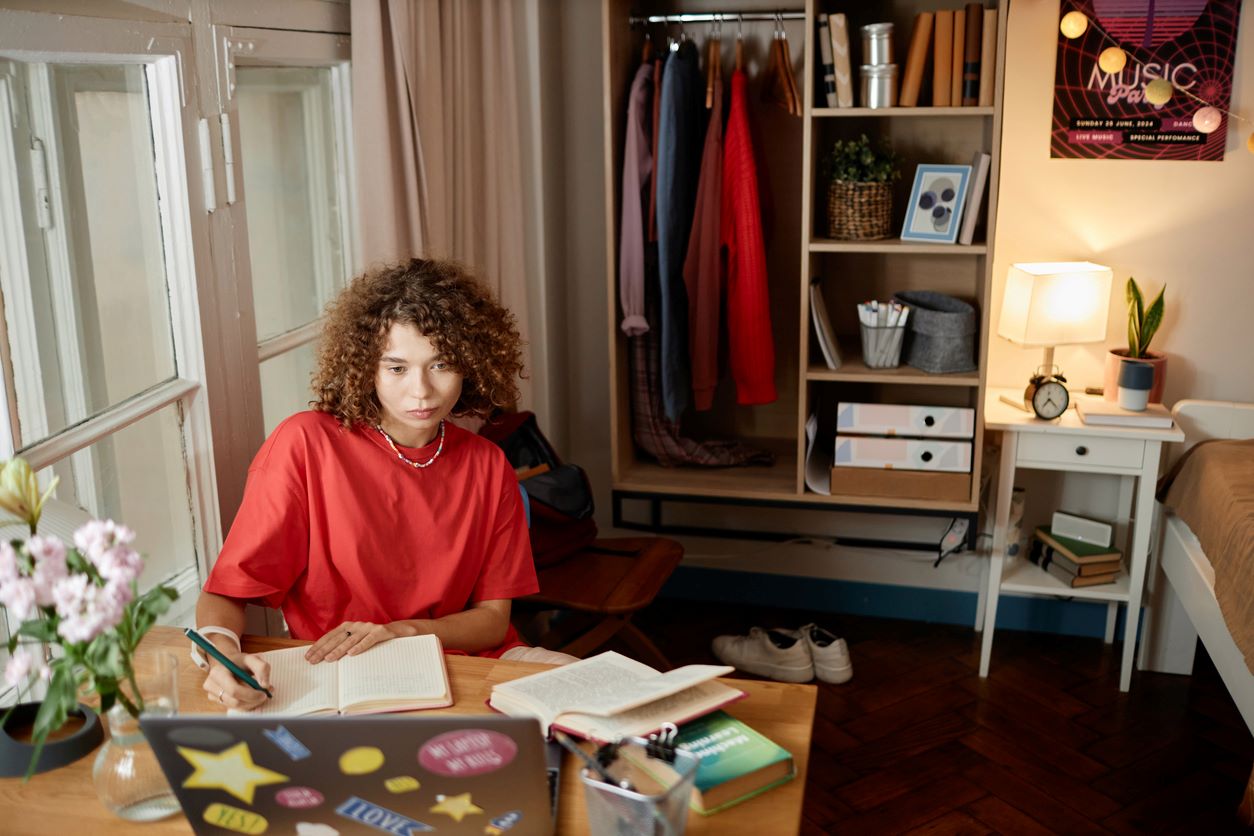 A college student studies at her desk in her dorm after moving back to college.