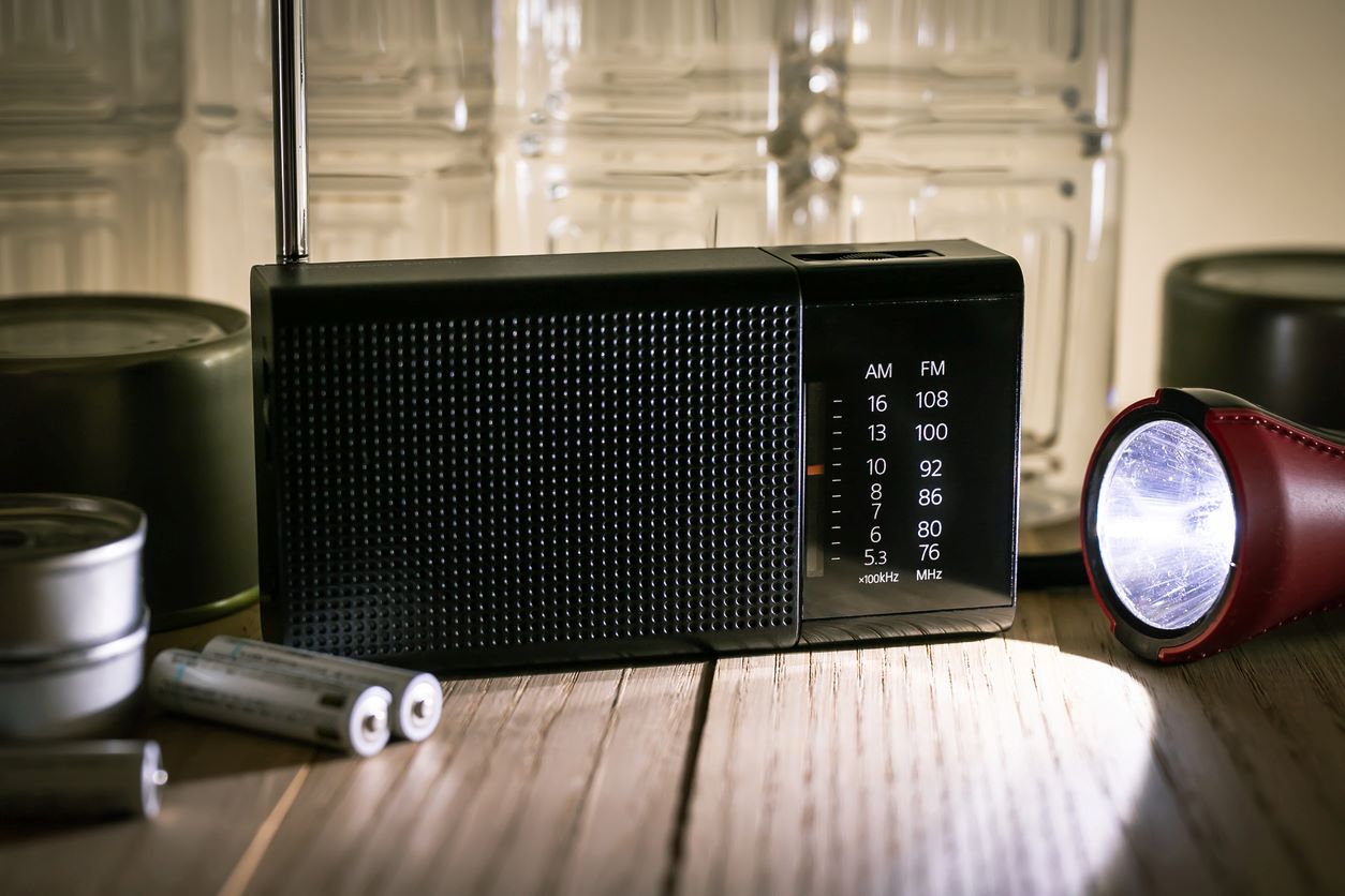 Closeup of batteries, a radio, and a flashlight. 