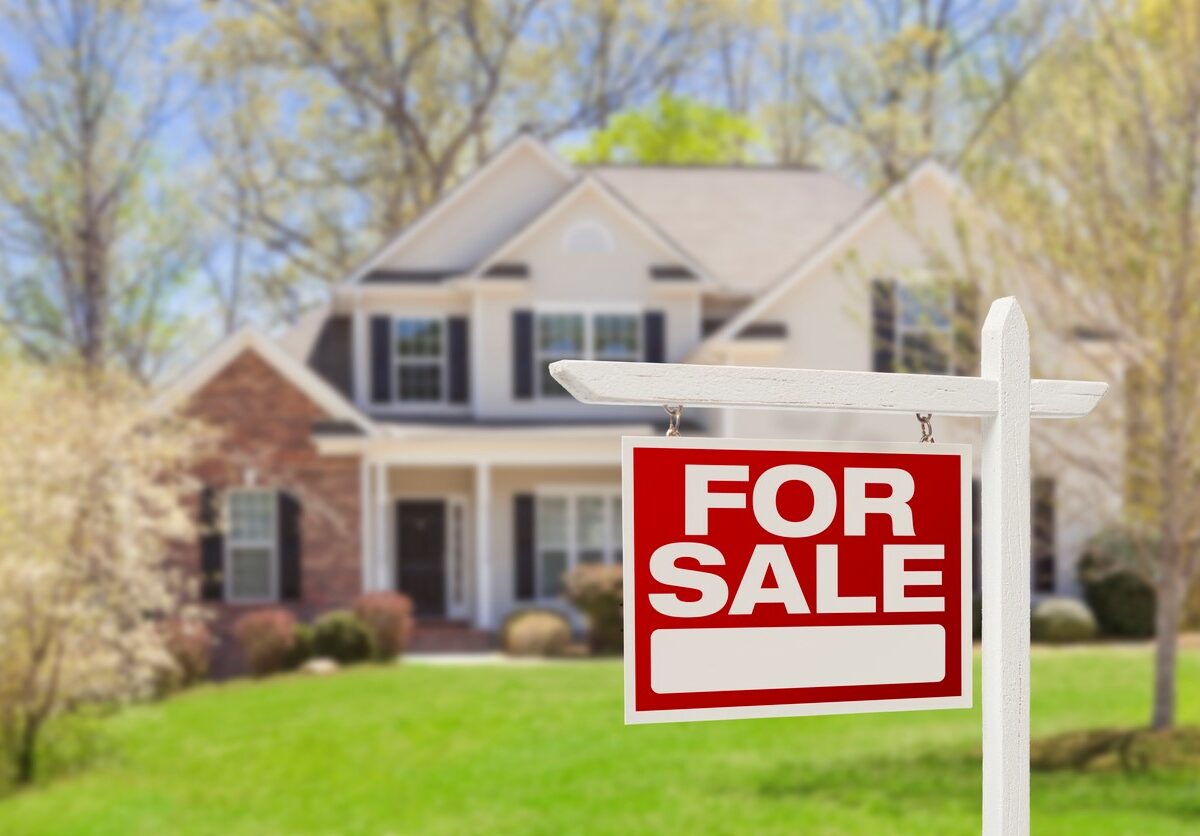 beautiful home with a “for sale” sign in the front yard.