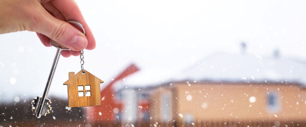 A person holds the key to their new home in the middle of a snowy winter day.